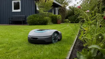 Kompakt robotplæneklipper der følger kanten af en velplejet haveplæne